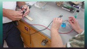 photo showing a battery hooked up to probes in a blue solution
